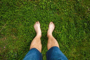 Bare feet of a man standing on a green grass