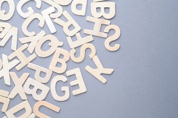 Scattered wooden white alphabets on gray background, English letters for learning English concept,...