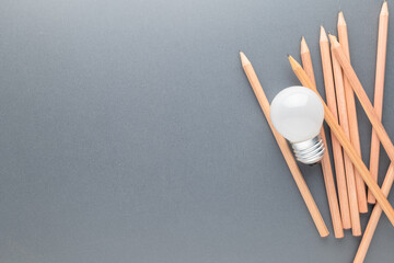Small light bulb on the pile of brown pencils with copy space, creative writing, knowledge and learning concept