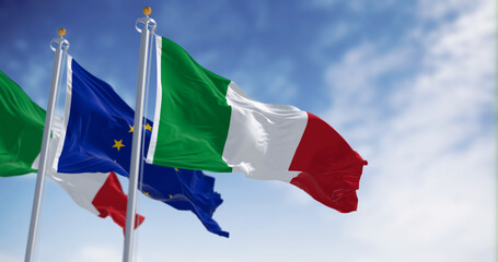 Naklejka na ściany i meble Italy and the European Union flags waving in the wind on a sunny day