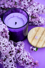 Obraz na płótnie Canvas Purple candle next to purple lilac. spa concept. purple background