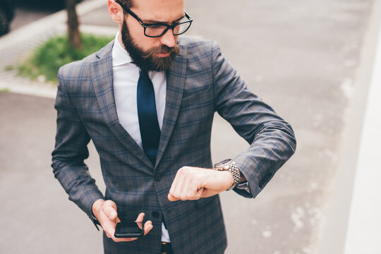Young professional elegant bearded businessman outdoors checking time