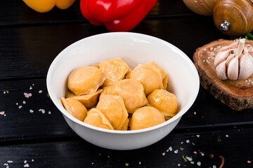 Boiled sweet dumplings with cottage cheese on the background of sweet pepper, spices, garlic and herbs.