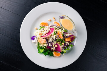 Green salad with cabbage, tangerines, nuts, parsley, green peas and sauce.