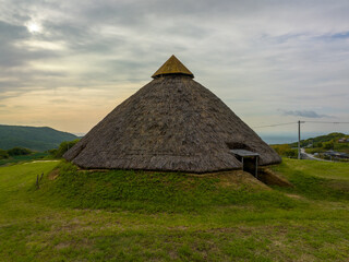 Historic Jomon thatched roof hut on grassy Awaji Island hill 