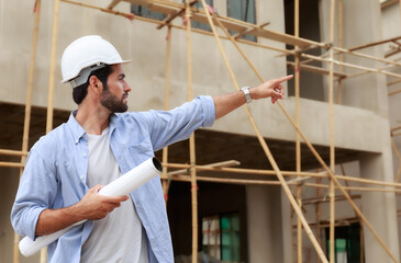 Young male architect, engineering consultant On a construction site holding a blueprint in hand Building inspector.