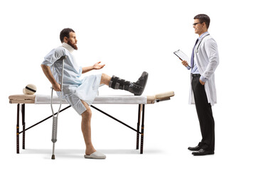 Obraz premium Patient with an orthopedic boot and neck collar sitting on a therapy table and talking to a therapist
