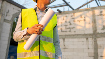 An Asian Engineering man wearing safety helmet analyzing construction drawings in construction site