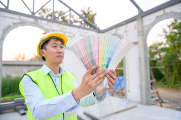 An Asian Engineering man wearing safety helmet selecting color in construction site