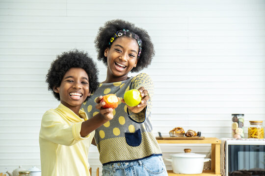 Two African american children enjoy and happy showing red and green apple is bite, Enjoy eating moment. Healthy food and kid concept.​