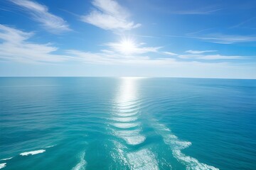 Fototapeta na wymiar 海の水面に日光が輝く、空は美しい雲と青空