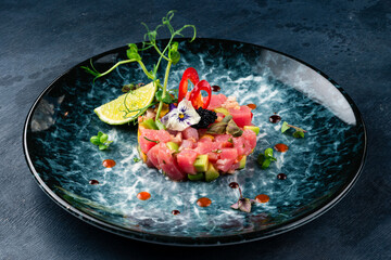 Tuna tartare with avocado, lime, pepper and flying fish caviar in a plate.