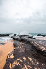 Waves crashing on black rock and sand