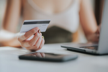 online payment Young woman's hand holding a credit card and using a smartphone for online shopping.