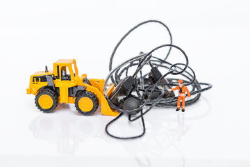 Tangled earphones cable with miniature worker and front loader truck isolate on white background, worker clearing messy wire