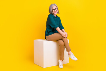 Full body photo of charming cheerful person sit podium good mood isolated on yellow color background