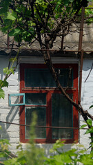 Fototapeta na wymiar Old wooden window painted red. A wall of a house with a red wooden window. A wooden window with an open window leaf