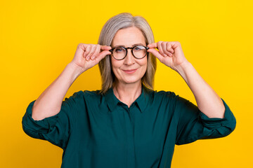 Fototapeta premium Portrait of clever cheerful aged lady agent hands touch glasses isolated on yellow color background