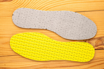 One pair of latex insoles on a wooden table, top view.