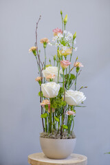 Vertically constructed composition of flowers in pots. Floral arrangement with white roses