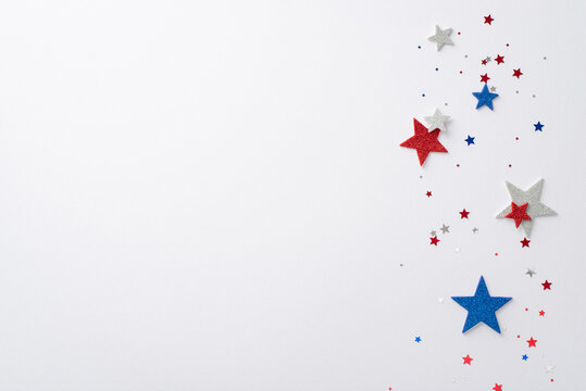 American Independence Day concept featuring top-view composition of festive party decorations: glitter stars and sparkle confetti against a white backdrop with empty space for text or advertising