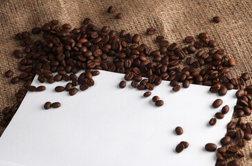 Blank sheet paper and coffee beans on burlap. Top view. Copy space