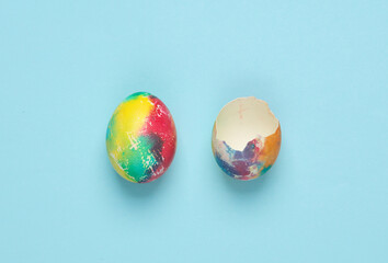 Whole and broken colored Easter egg on a blue background. Minimal easter concept