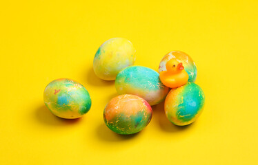 Colored Easter eggs with toy rubber duck  on yellow background