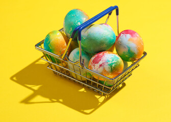 Supermarket basket with Easter eggs on yellow background. Minimalism Easter still life