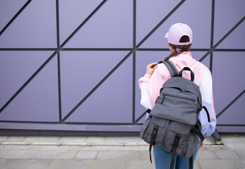Back view a woman in a sporty style with a backpack against the background of the wall. No face....