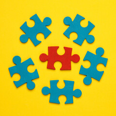 Blue and red jigsaw puzzle pieces on a yellow background. Business concept