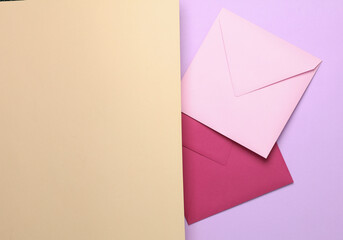 Two square colored envelopes on a pastel half background