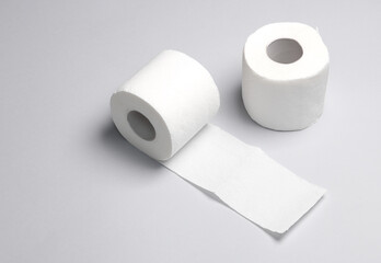 Two rolls of white toilet paper on a blue background with a shadow