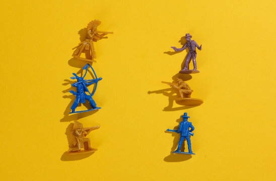 Wild west scene. Plastic cowboy and american indian gunfight on yellow background. Creative layout