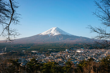 View of mount fuji with blue sky. In the foreground is a city.