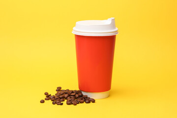 Take-out cardboard coffee cup with lid and coffee beans on yellow background