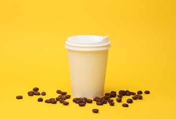 Take-out white cardboard coffee cup with lid and coffee beans on yellow background