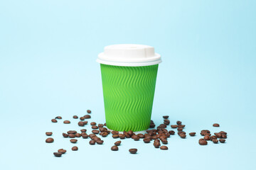 Take-out blue cardboard coffee cup with lid and coffee beans on  blue background