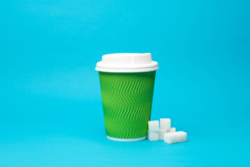 Disposable cardboard cup and sugar cubes on blue background