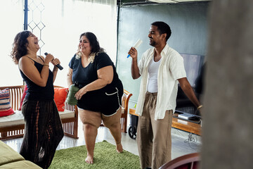 Friends dancing and singing together at home on a weekend