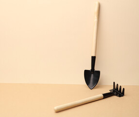 Set of miniature garden tools (rakes, shovels) on brown beige background. Creative layout