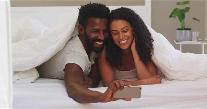 Love, selfie and couple in bed happy, relax and bond while resting in their home together. Smartphone, photo and social media influencer people pose for profile picture or blog in hotel room