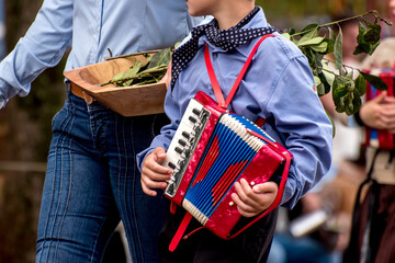 Boy next to his mother passing by in parade with harmonica in hand
