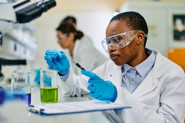 Black female microbiologist doing research in pharmaceutical laboratory.