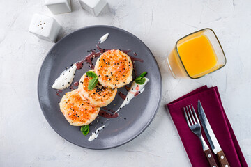 Sweet breakfast cheese pancakes with jam, sour cream, sesame seeds, mint and glass of juice.