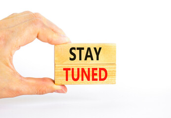 Stay tuned symbol. Concept words Stay tuned on wooden blocks on a beautiful white table white background. Businessman hand. Business, support, motivation, psychological stay tuned concept. Copy space.