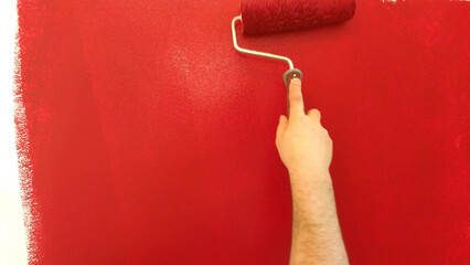 painting a wall. painting the wall in red with a roller