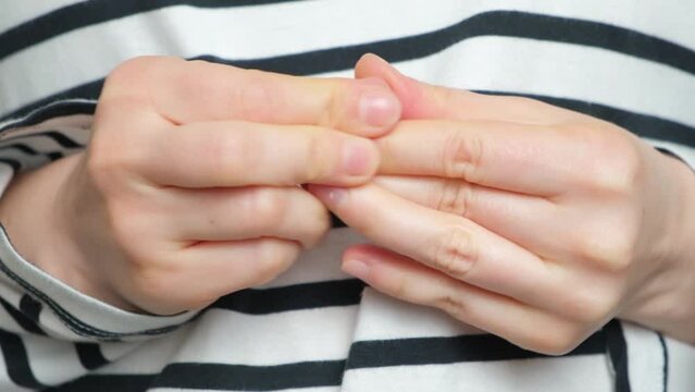 A woman wrings and rubs her fingers, anxiety and stress, palms sweat.