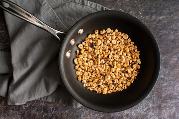 Toasted Hazelnuts in a Stainless Steel Measuring Cup: Overhead view of chopped cobnuts after...