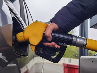 Mão a segurar a bomba de combustível e reabastecer o carro no posto de gasolina
